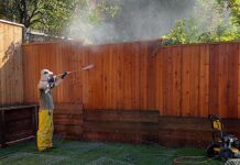 Man pressure washing a fence.